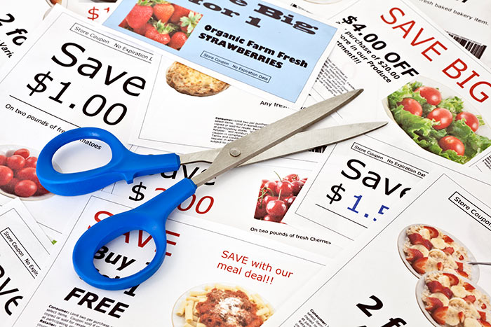 Newspaper coupons laid out on a table with scissors nearby
