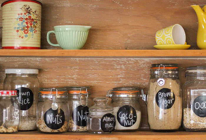 A pantry shelf with vintage jars and labels with dry goods and baking supplies