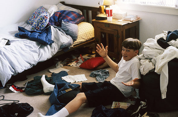 Young boy sitting on the floor of his messy room