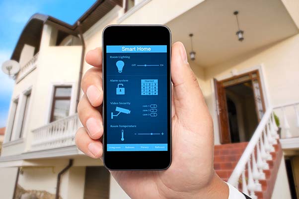 A man's hand holding his smart phone with a home security app before leaving on vacation.