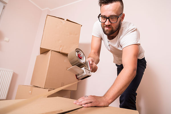Young man taping boxes.