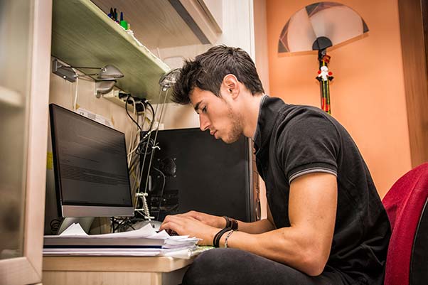 Young man in his college dorm doing homework.