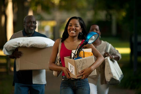 Young woman and her parents carrying her things as she heads off to college