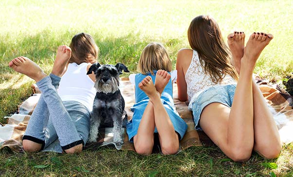 Three kids laying on the grass with their dog enjoying the last days of summer.