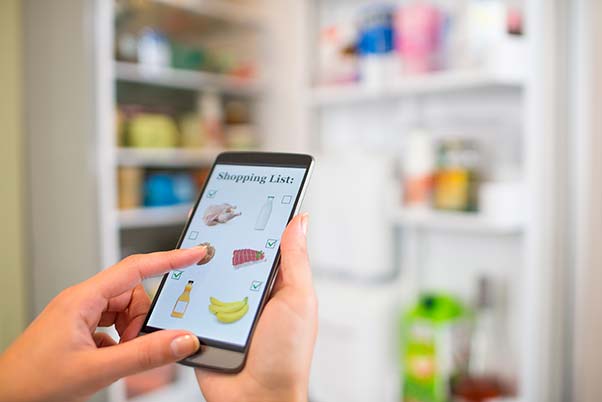 View of a person using a smart phone shopping list app to make a list for replenishing the pantry.