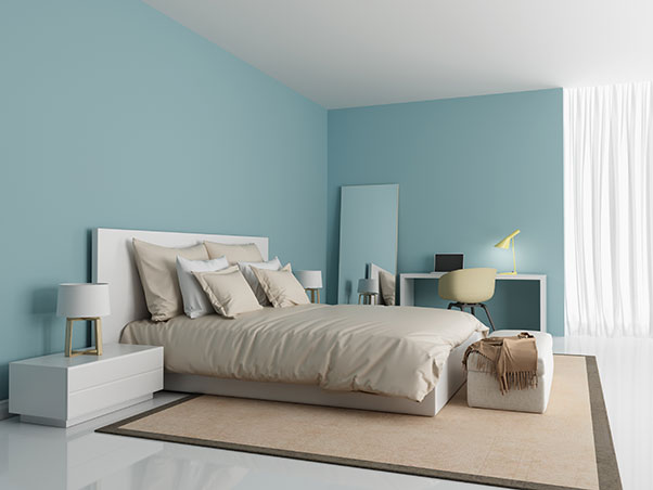 Guest room painted with light blue walls and accents and double bed with throw pillows.