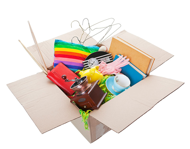 A box full of household stuff (teacup, piggy bank, coffee grinder, baseball, gloves, books, pillows, purses, hangers, drum sticks.) 