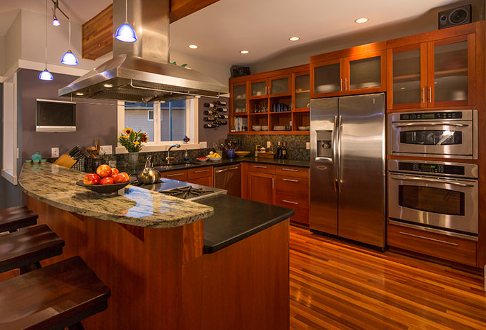 Modern kitchen with granite counter and rich wood flooring and cabinets.