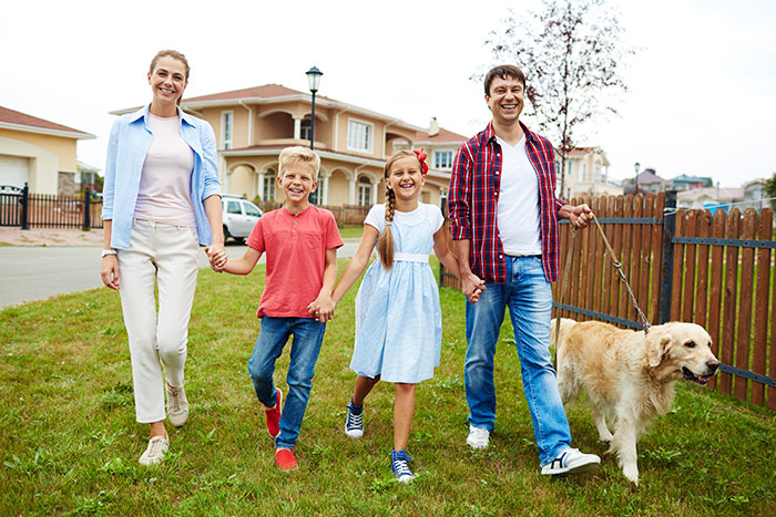 A family of four; mother, father, daughter and son, with their dog, walking in their new neighborhood