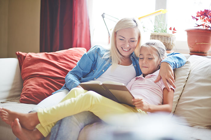 A mom and daughter reading a book on the sofa at their new house