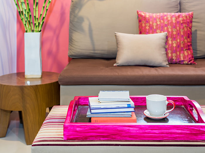Home interior featuring a sofa with colorful throw pillows and pink serving tray as focal point for decor.
