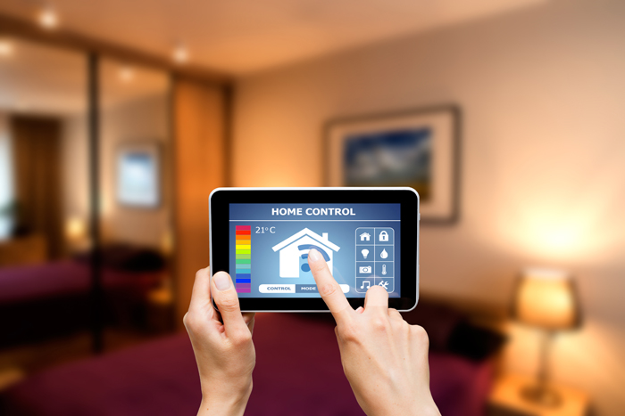 Hands holding a smart phone displaying a home energy management app with household blurred background