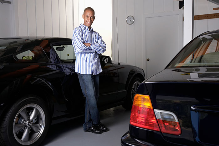 A man standing in his garage with two cars parked inside
