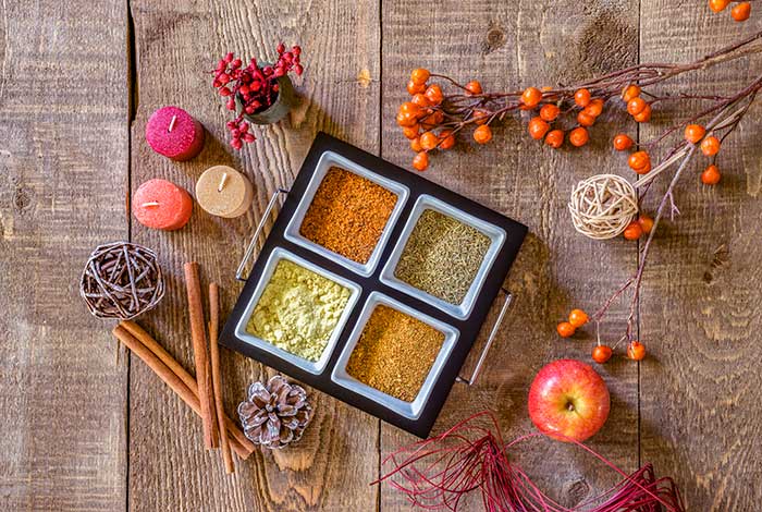 Autumn colored items: spices, leaves, apples, candles, sprigs arranged on wood pallet (decorating ideas for fall season)