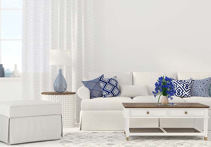 White couch, chair and living room furniture with blue winter accent pillows and lamp vase