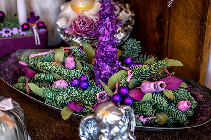 Purple and pink hued flowers with evergreen pine cuttings in a wintery centerpiece