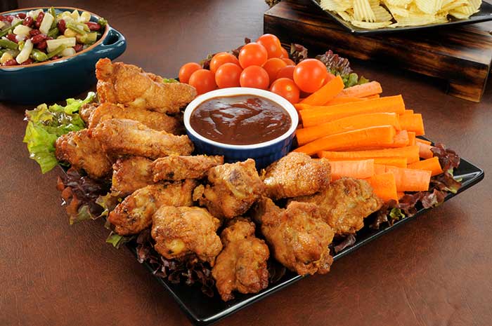 Party tray with chicken wings, carrot sticks, cherry tomatoes and dip