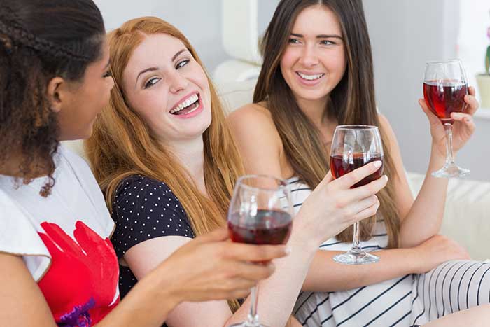 Three women drinking wine and smiling 