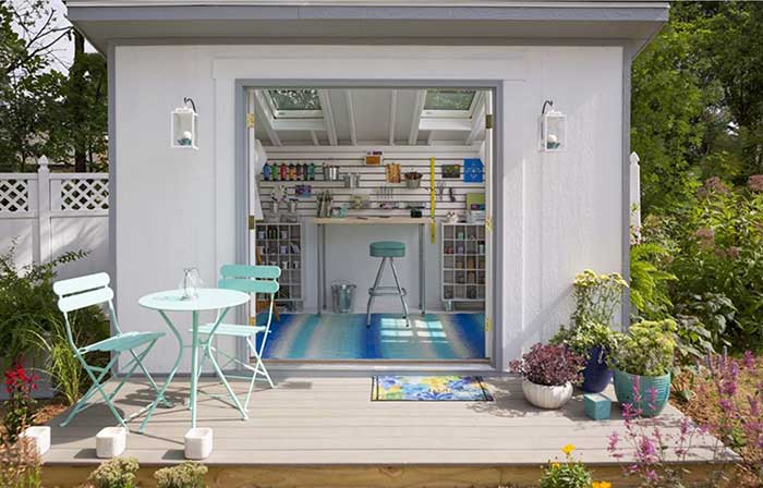An exterior shed with feminine decor, pretty patio furniture and interior setup as an art studio 