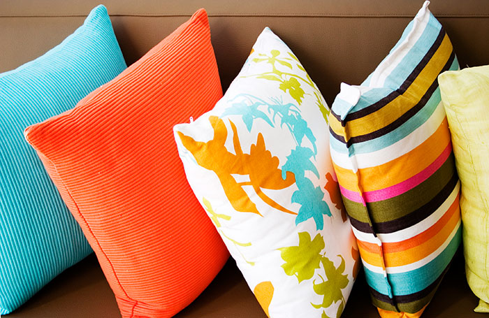 Multiple throw pillows lined up in a variety of colors and patterns for Spring home decor