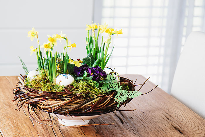 Spring style Easter centerpiece wicker twist with greens, painted eggs and daffodils