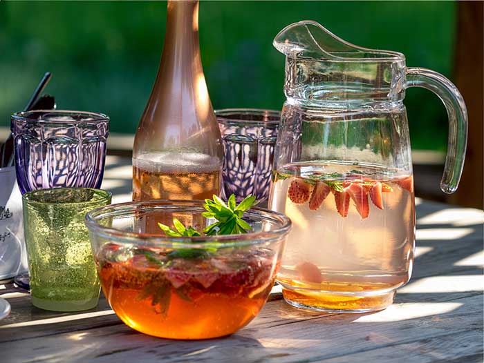 Multi-colored lemonade pitcher & glasses and decorations on a summer picnic table