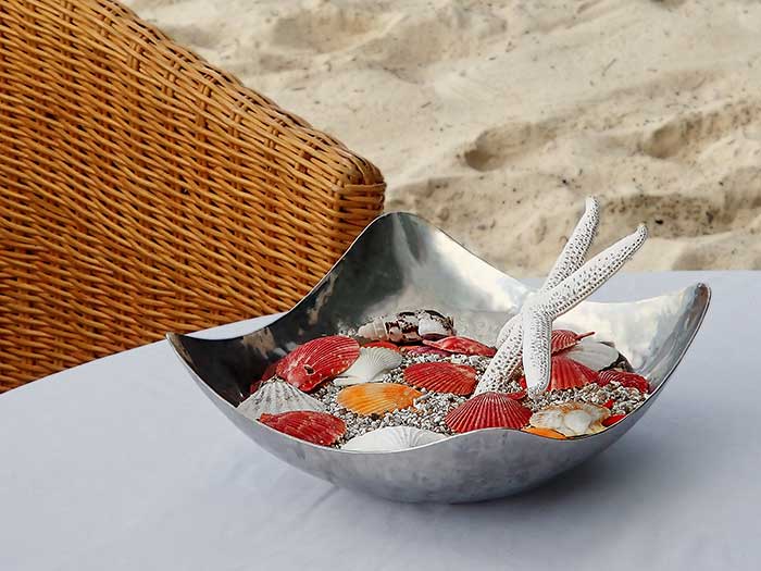 Table centerpiece dish with sand and seashells for a beach themed summer party