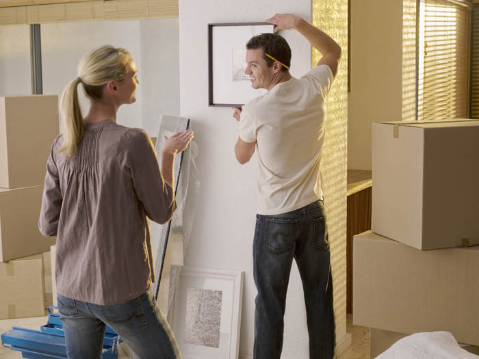Man hanging picture while woman watches
