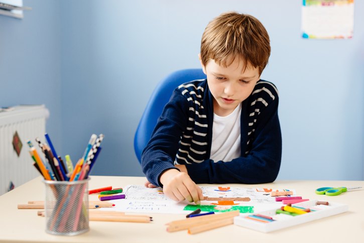 Young boy coloring at desk