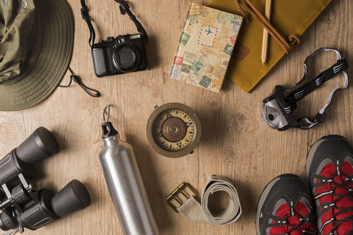 Overhead view of travel equipment for a backpacking trip on wooden floor. Adventure travel concept.