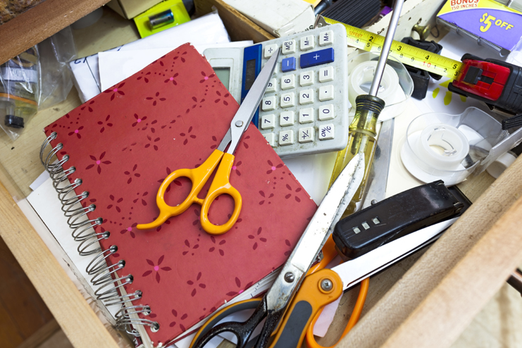 Cluttered kitchen drawer filled with a confusing jumble of everyday objects.