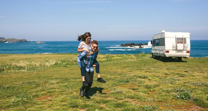 Man giving woman piggyback ride near RV