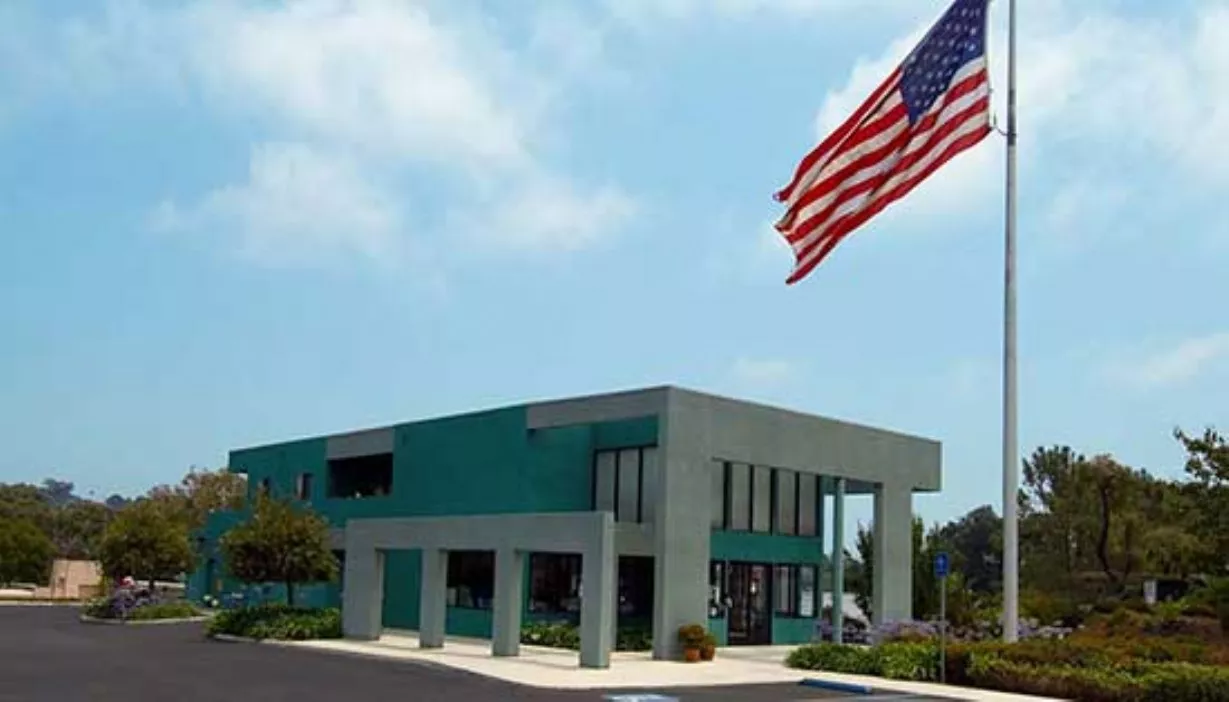 Rental office adjacent to parking lot with flag pole and American flag flying