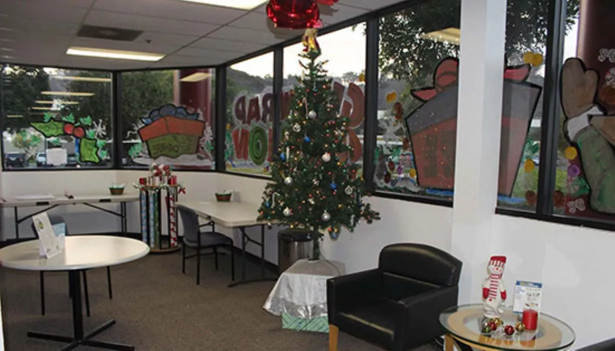 Rolls of gift wrap, Christmas tree, and other holiday decor for the seasonal gift wrapping station in the rental office