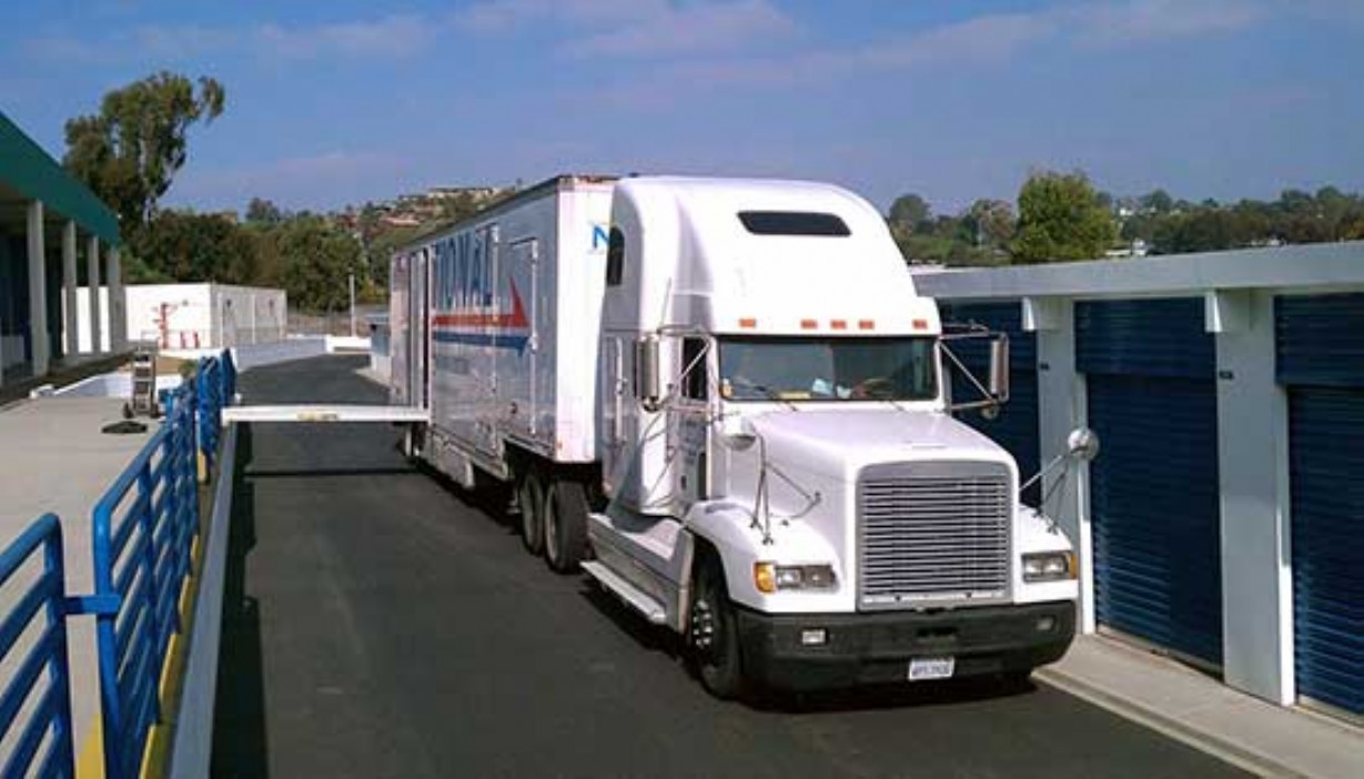 Storage facility loading dock with a large moving van pulled up to unload