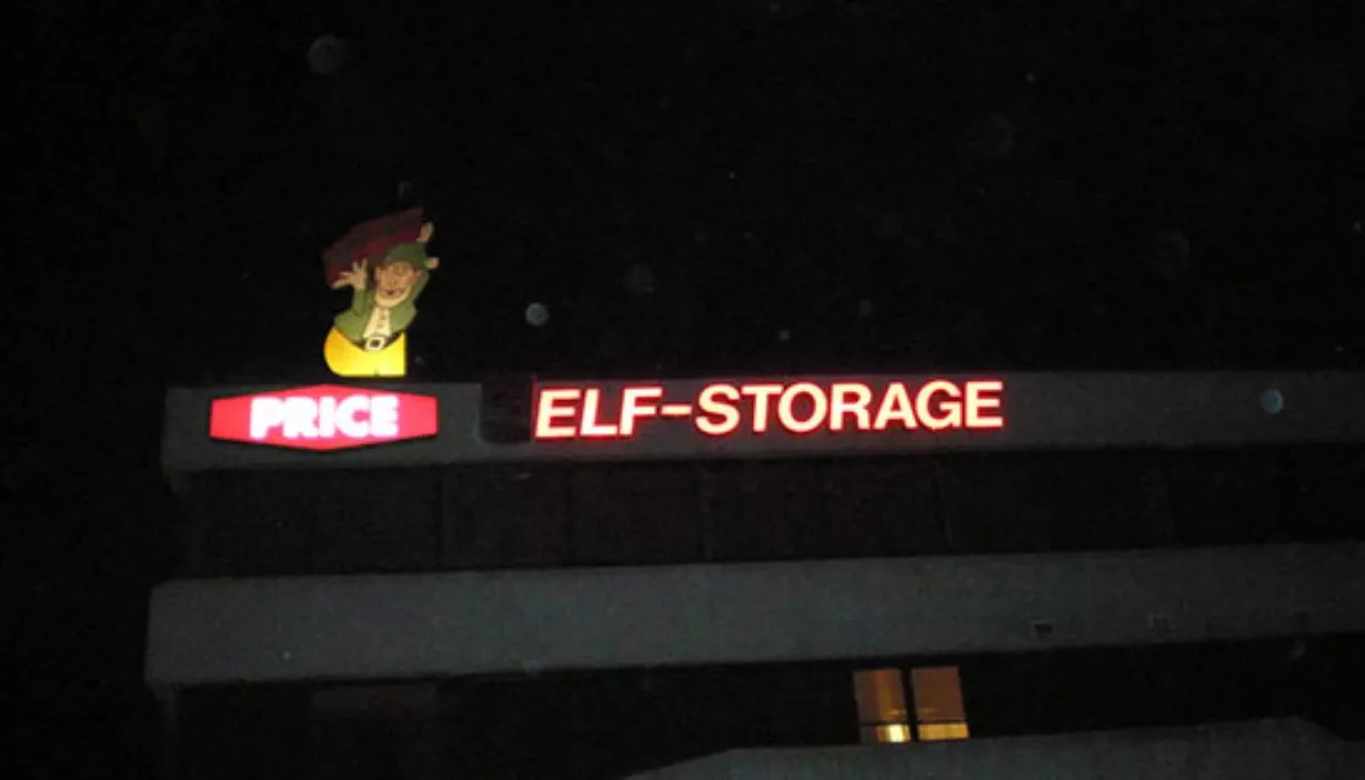 Main building sign lit up at night with elf character on the roof