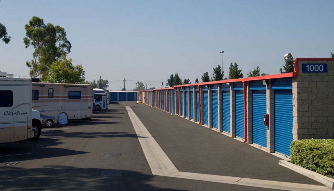 Drive aisle with vehicles and RVs parked left and storage units right