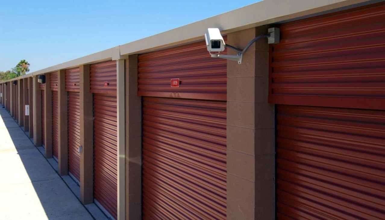 Very large drive up storage units with roll up doors and security camera on the building