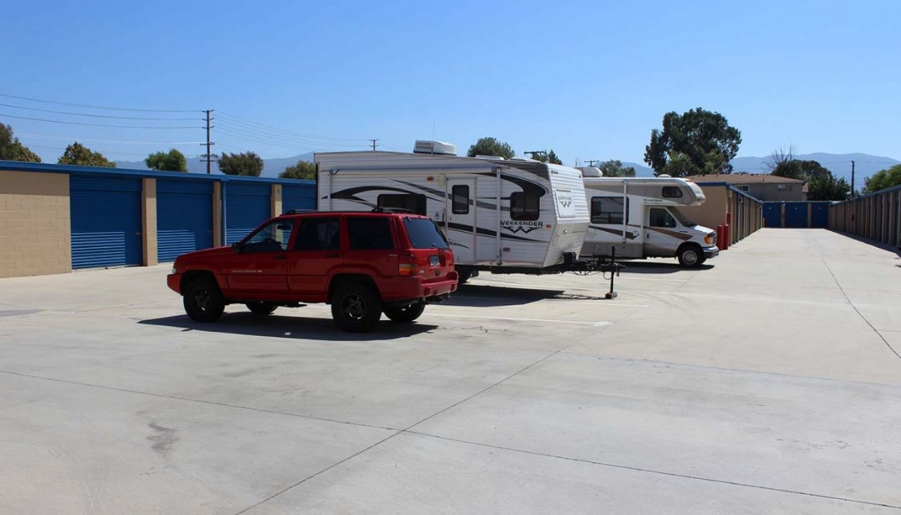 An SUV, travel trailer and small RV parked in vehicle storage spaces