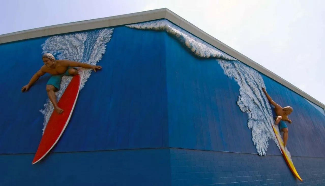 Price Self Storage Pacific Beach environmental art of two surfers riding waves on the side of the building