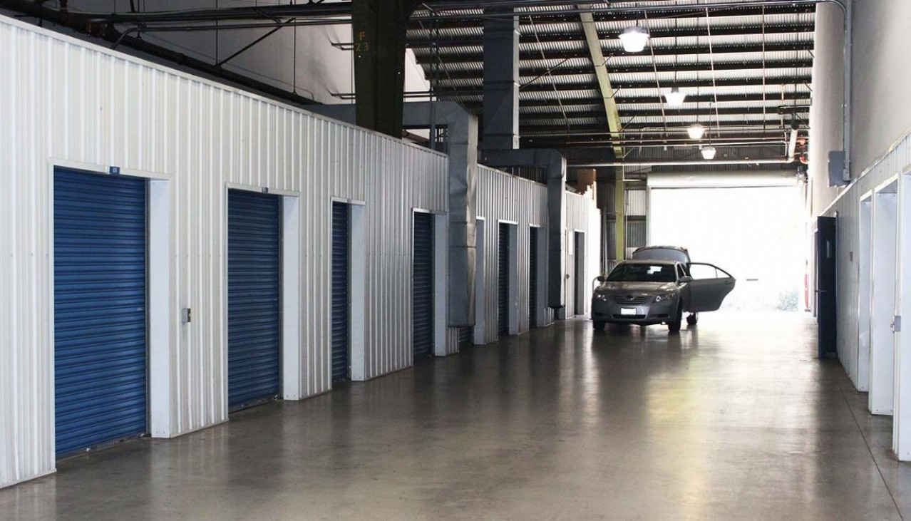 Indoor storage facility with car pulled in next to storage unit