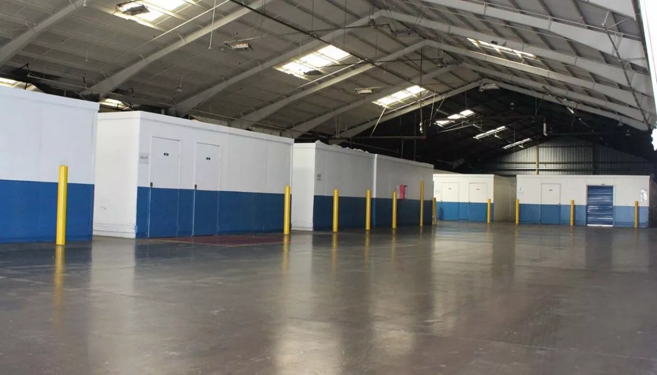 Storage facility hallway with variety of storage units with roll up doors
