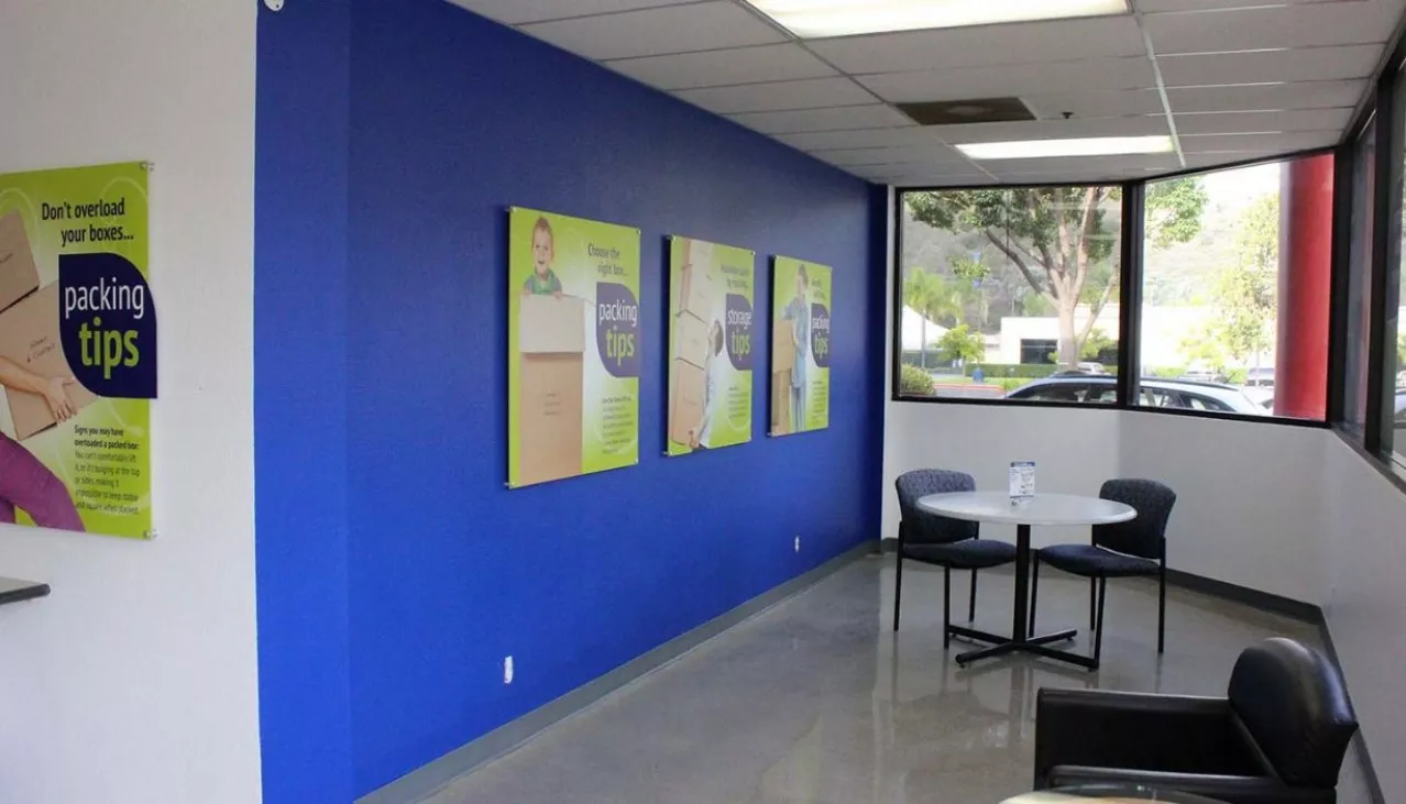 Green signs on blue wall next to a table and chairs
