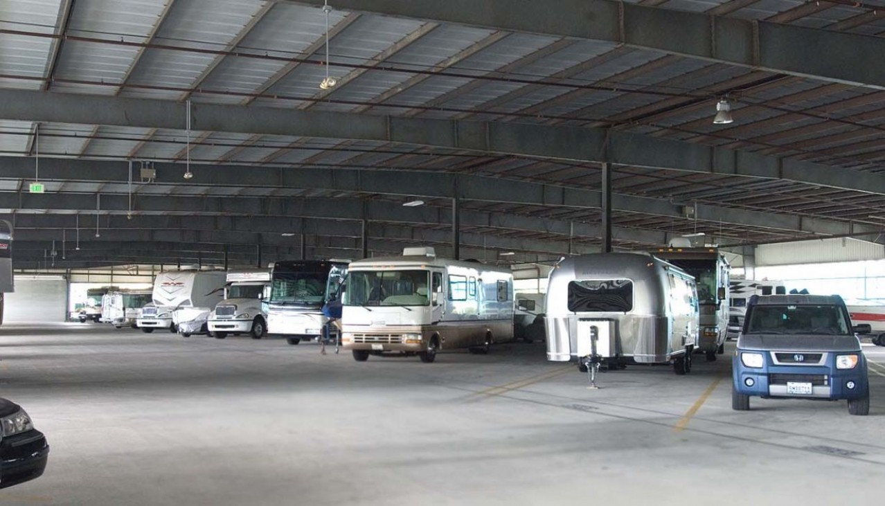 Motorhomes, cars, boats, and trailers parked in the indoor vehicle storage facility